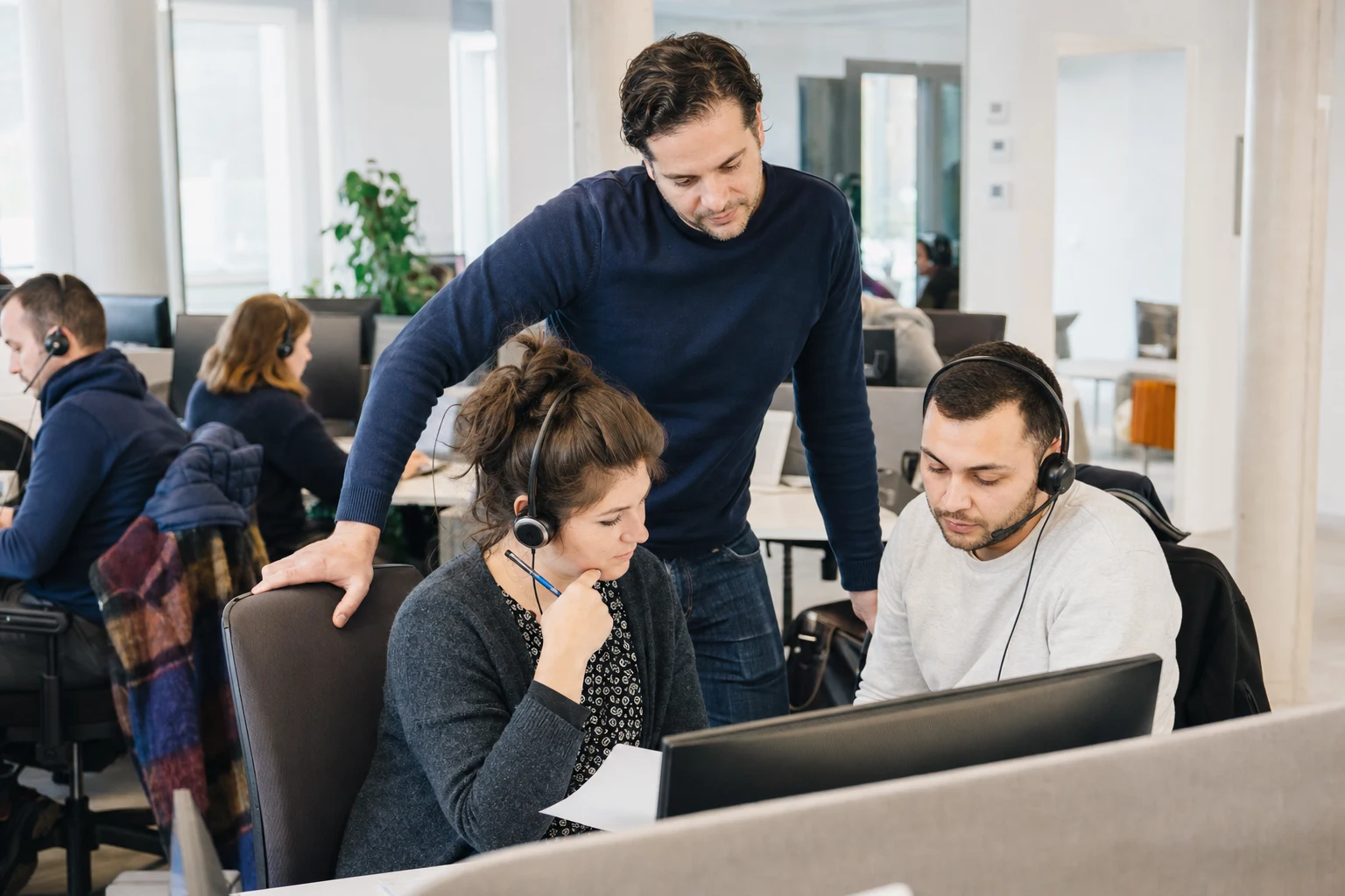 Conseillers client avec casques examinant une escalade dans un centre de contact lumineux.